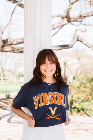 photo of a brown haired woman wearing a Virginia shirt leaning against a white column